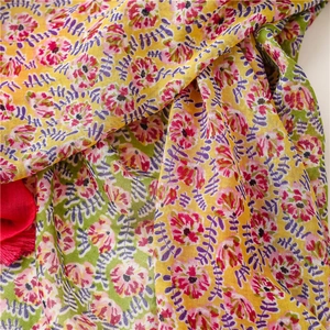 Detail of floral print scarf with pink flowers and fuchsia tassel fringe accents