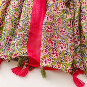 Detail of floral scarf featuring vibrant flower prints and bi-color tassels on a soft fabric