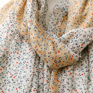 Detail view of the floral print cotton scarf with blue leaves and yellow borders