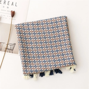 Detail of navy and brown geometric cross pattern scarf with decorative fringe tassels