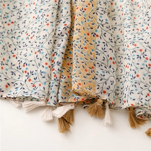 Detail of floral linen-feel scarf showing soft texture and bicolor fringe tassels
