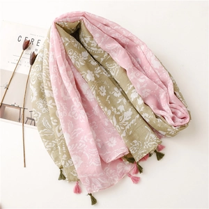 Détail d'une écharpe en coton rose et vert avec imprimé floral et petits pompons