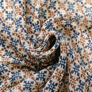 Close-up of geometric diamond print texture and fringe detail on beige cotton scarf