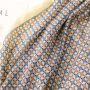 Detail of dark blue and caramel geometric snowflake pattern on light cotton-linen scarf