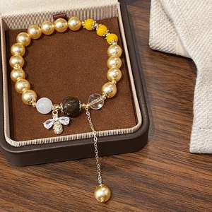 Bracelet de perles dorées avec pendentif abeille en zircon et glands dans un coffret