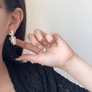 Elegant flower drop earrings with white pearls and red bead center on female model