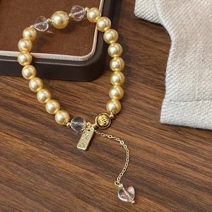 Handmade golden pearl bracelet with crystal beads and heart pendant on velvet tray