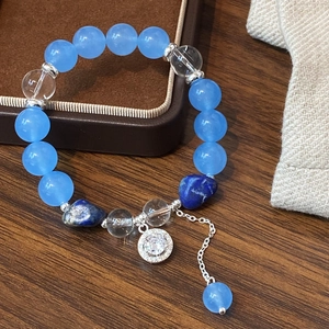 Sky blue beaded bracelet with aquamarine stones and silver charms on wooden surface
