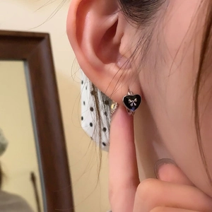 Black heart hoop earrings with silver bow accent shown on model for a trendy sweet look