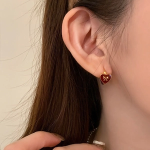Gold-plated bow earrings with red heart enamel charms shown on model for elegant style