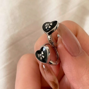 Detail of heart-shaped earrings with black enamel and silver bowknot design