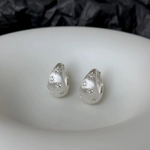 Macro shot of silver water drop earrings featuring brushed texture and star zircon stones