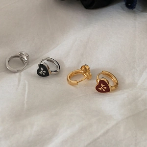Close-up of black and burgundy heart huggie earrings with engraved star patterns