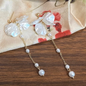 Detail of vintage flower earrings with white petals, pearls and long gold tassels