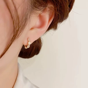 Boucles d'oreilles créoles dorées avec perles d'opale blanche et zircons sur mannequin