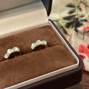 Détail de boucles d'oreilles créoles dorées avec opales et zircons dans un coffret à bijoux