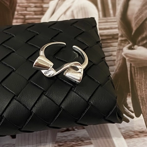 Polished silver bow ring with elegant twisted design shown on a luxury leather texture