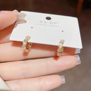 Gros plan sur les boucles d'oreilles dorées en C avec pierre œil-de-chat et zircons