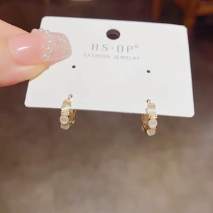 Détail de boucles d'oreilles dorées avec pierres œil de chat et zircons sur carte