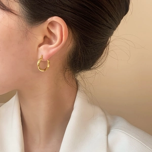 Élégantes boucles d'oreilles créoles dorées portées par un mannequin