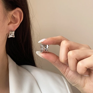 Polierte silberne geometrische klobige Ohrringe im minimalistischen Design an einem Model