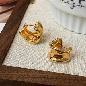 Detailansicht der dicken, unregelmäßigen goldenen Wellenohrringe auf Holztablett