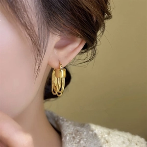 Detail of gold chain tassel earrings with square accent on model for elegant styling