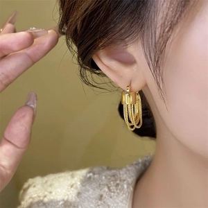 Close-up of elegant gold multi-layered tassel chain earrings on a female model