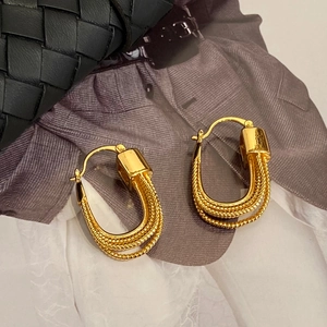 Macro shot of elegant gold layered U-shape chain earrings with fine woven texture