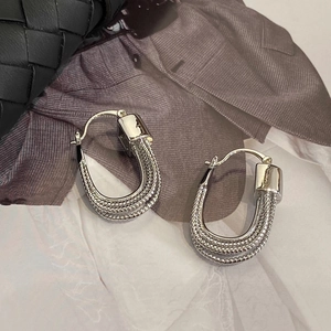 Detail of elegant silver U-shaped layered bead chain earrings on fashion magazine background