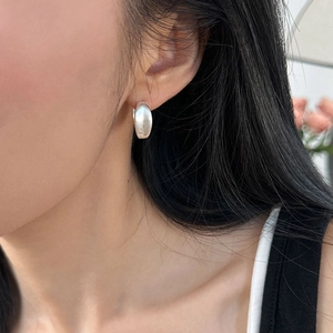 Close-up of minimalist matte silver hoop earrings worn by a model for a sleek look