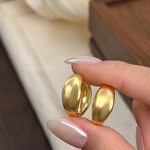 Close-up of golden brushed metal earrings with elegant matte texture and thick hoop design