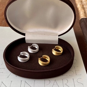 Detail of brushed gold and silver geometric hoop earrings in a jewelry box
