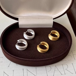 Macro detail of gold and silver brushed metal hoop earrings in a velvet jewelry box