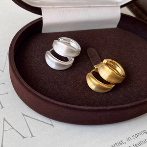 Macro shot of gold and silver brushed metal round hoop earrings on brown velvet