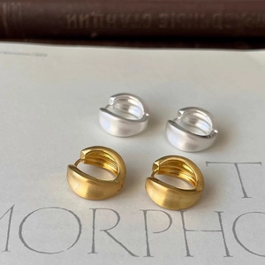 Detail of brushed gold and silver geometric hoop earrings with vintage matte texture