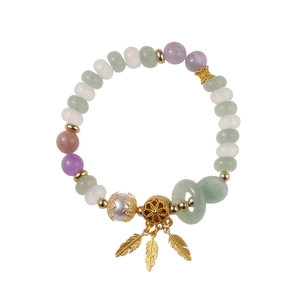 Bracelet en perles de pierres naturelles avec breloques plumes dorées sur fond blanc