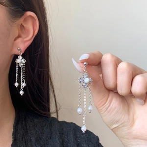 Elegant silver four-leaf flower earrings with pearl tassels and zircon accents on model
