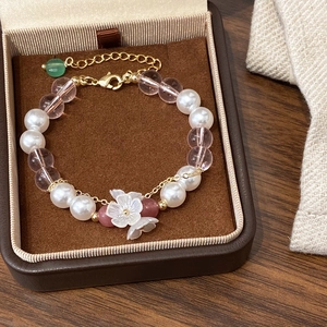 Handmade beaded bracelet with white shell flowers, pearls, and pink crystals on gold chain