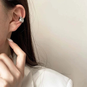Minimalist silver ear cuff with irregular hammered texture on female model ear