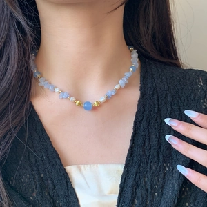 Elegant pearl and blue natural stone necklace shown on a model neck with a black lace top