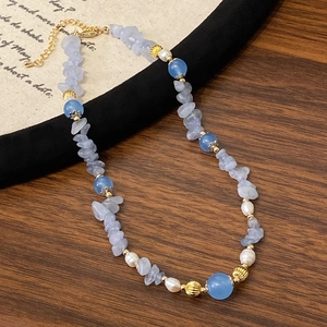 Handmade necklace with blue stones, freshwater pearls, and golden metal accents