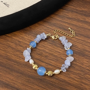 Macro view of blue agate and pearl beaded bracelet on textured dark wood background