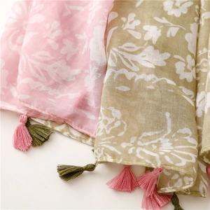 Gros plan d'écharpes à fleurs rose et olive montrant la texture coton et les franges