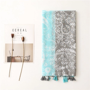 Détail d'une écharpe en coton à motif paisley avec pompons bleu et gris pour le soleil