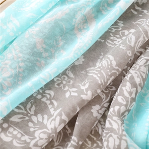 Gros plan sur une écharpe bleu clair effet coton avec motifs cachemire et fleurs blanches