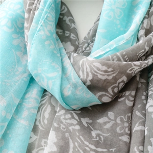 Gros plan du motif floral et de la texture du foulard en coton turquoise et gris