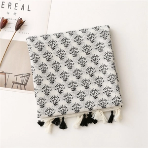 Detail view of cotton linen scarf with black floral print and stylish fringe tassels