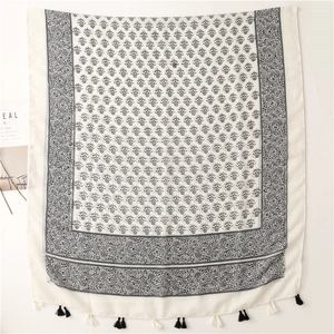 Detail of cream floral scarf with black ethnic prints and fringed edges on white background