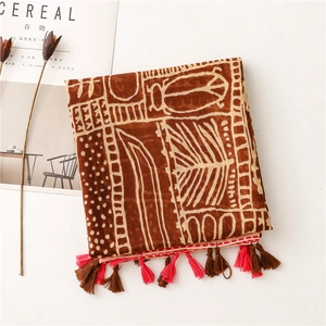 Detailed view of bohemian tribal print scarf with decorative red and brown tassels